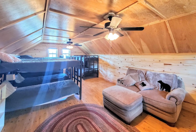 bedroom featuring wood walls, hardwood / wood-style floors, ceiling fan, and vaulted ceiling