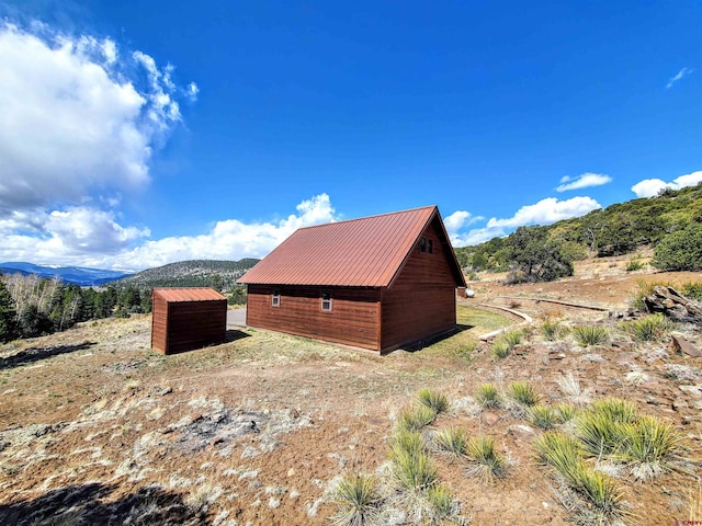 view of property exterior with an outdoor structure and a mountain view