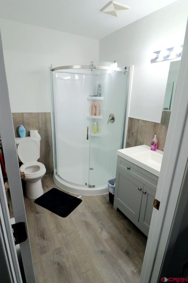 bathroom with hardwood / wood-style floors, vanity, toilet, and an enclosed shower