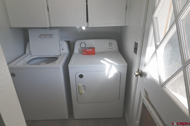 laundry area with separate washer and dryer and cabinets