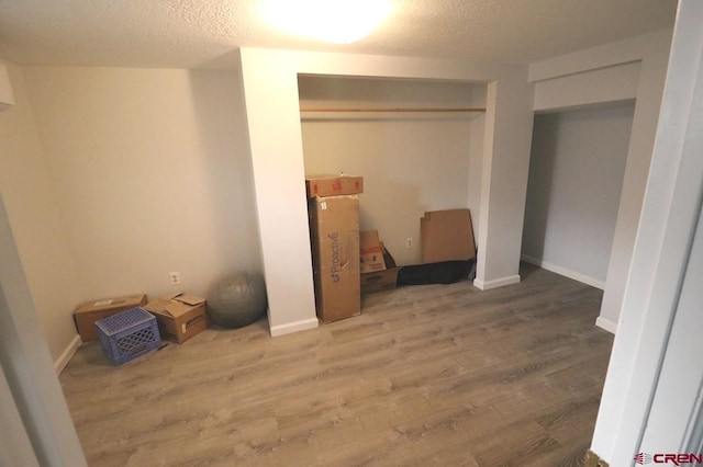 unfurnished bedroom featuring wood-type flooring, a textured ceiling, and a closet