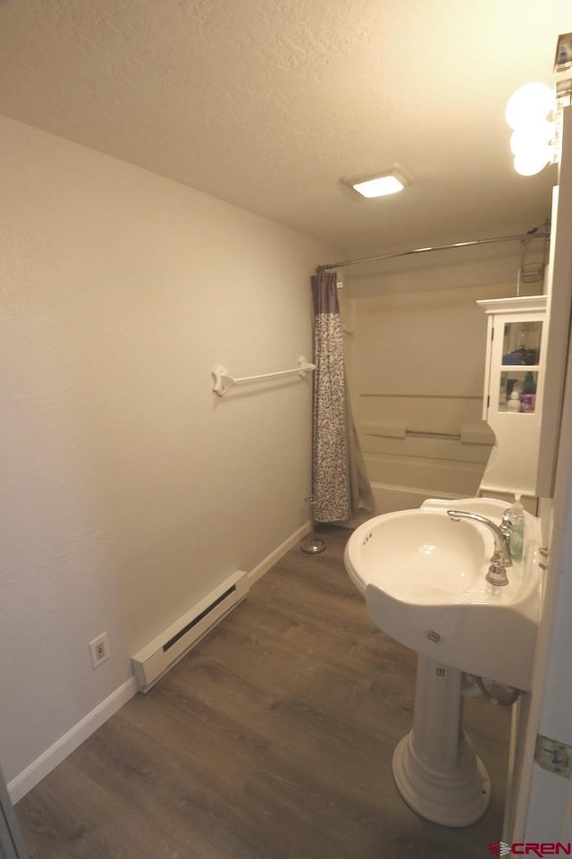 bathroom featuring wood-type flooring, a baseboard radiator, sink, and shower / bathtub combination with curtain