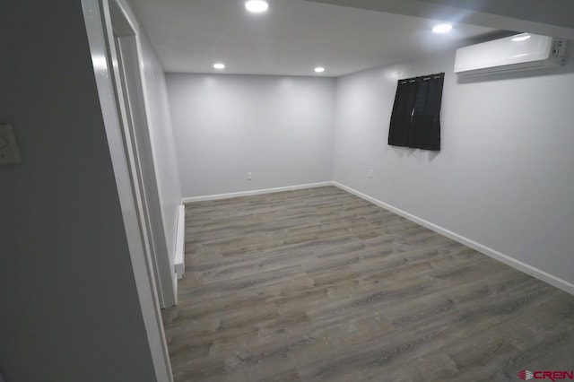 basement featuring hardwood / wood-style floors and a wall mounted air conditioner