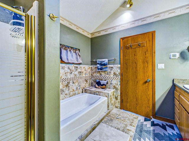 bathroom featuring vaulted ceiling, a bath, and vanity