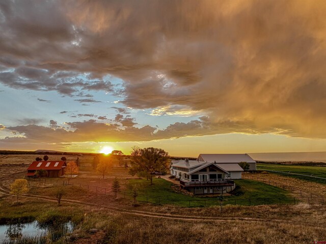 back house at dusk featuring a water view and a rural view