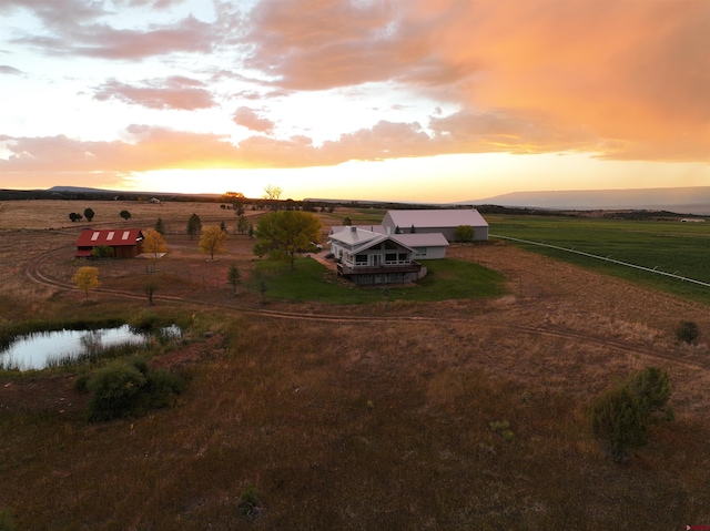 aerial view at dusk with a water view and a rural view