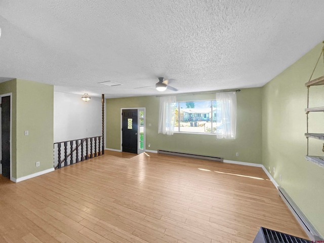 spare room featuring a baseboard heating unit, light hardwood / wood-style floors, and a textured ceiling