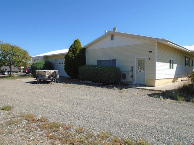 back of property with ac unit and a garage