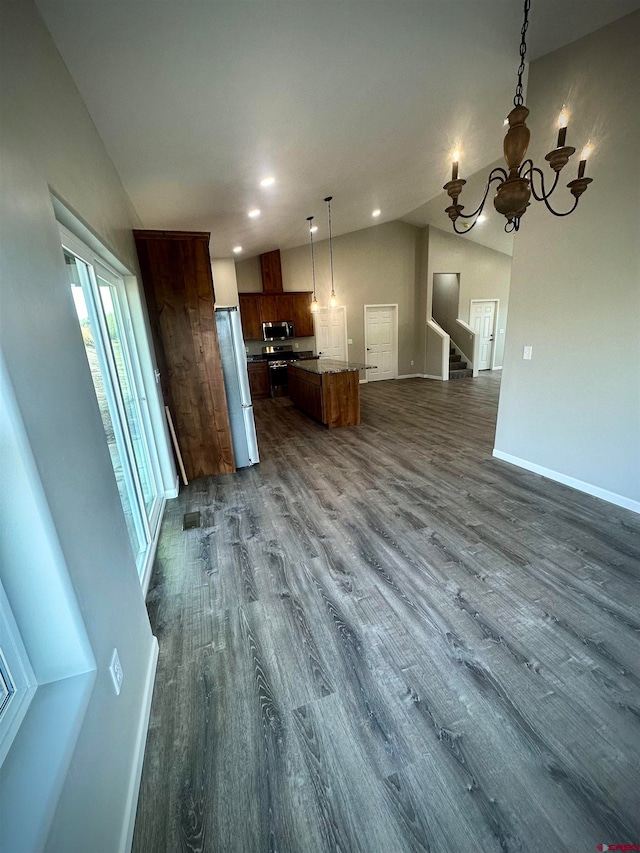 kitchen featuring lofted ceiling, hanging light fixtures, dark hardwood / wood-style flooring, appliances with stainless steel finishes, and a center island