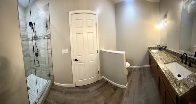 bathroom with toilet, an enclosed shower, hardwood / wood-style floors, and vanity