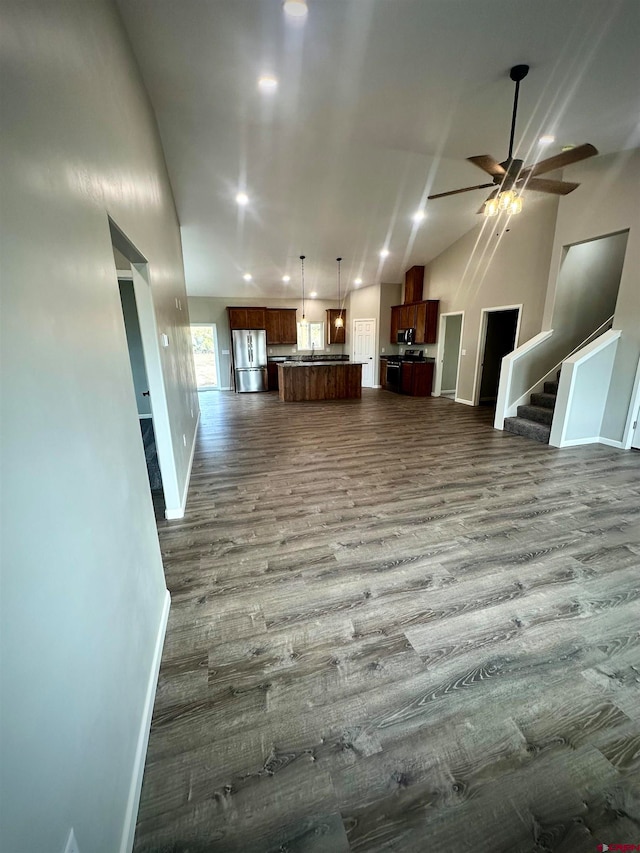 unfurnished living room with ceiling fan, wood-type flooring, and vaulted ceiling