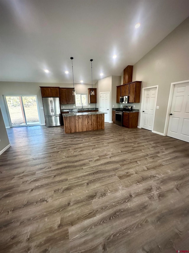 kitchen featuring dark wood-type flooring, stainless steel appliances, a center island, decorative light fixtures, and high vaulted ceiling