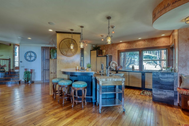 kitchen featuring a breakfast bar area, hanging light fixtures, light hardwood / wood-style floors, and kitchen peninsula