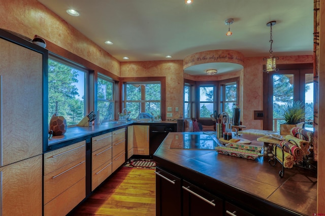 kitchen featuring light wood-type flooring, dishwasher, light brown cabinetry, and decorative light fixtures