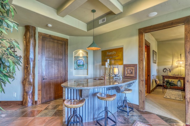 kitchen featuring hanging light fixtures, beam ceiling, a breakfast bar area, and dark colored carpet