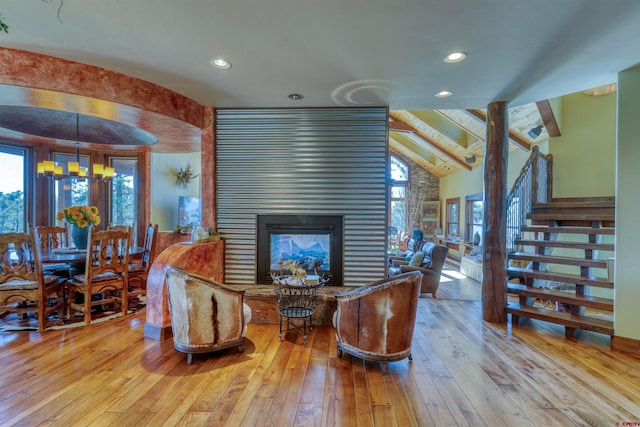 living room featuring a notable chandelier, a multi sided fireplace, vaulted ceiling with beams, and hardwood / wood-style floors