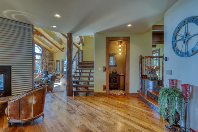 entryway featuring a fireplace, lofted ceiling with beams, and light hardwood / wood-style floors