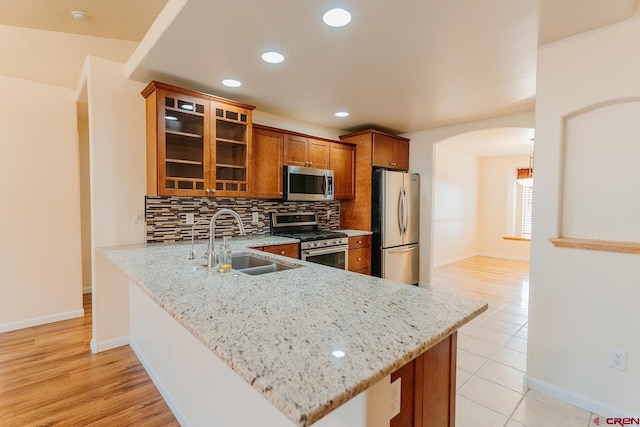 kitchen with kitchen peninsula, sink, light hardwood / wood-style flooring, and stainless steel appliances