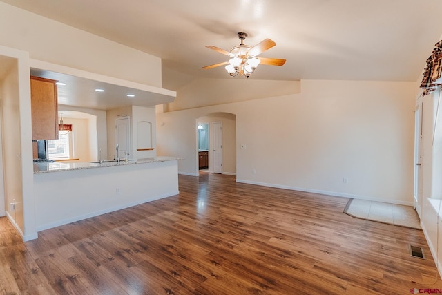 unfurnished living room featuring wood-type flooring, vaulted ceiling, and ceiling fan