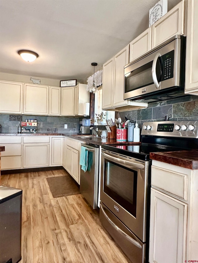 kitchen with appliances with stainless steel finishes, backsplash, light hardwood / wood-style floors, and decorative light fixtures