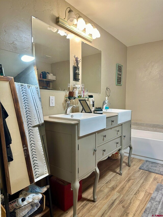 bathroom featuring vanity, hardwood / wood-style flooring, and a tub to relax in