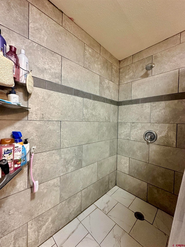 bathroom featuring a tile shower and a textured ceiling