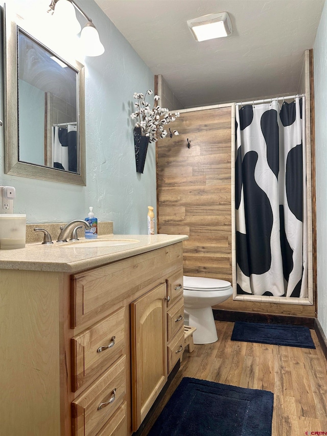 bathroom with wood-type flooring, vanity, toilet, and a shower with shower curtain