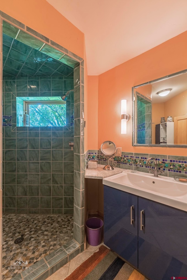 bathroom with backsplash, tiled shower, and vanity