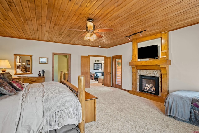 bedroom with a tiled fireplace, carpet, ceiling fan, and wooden ceiling