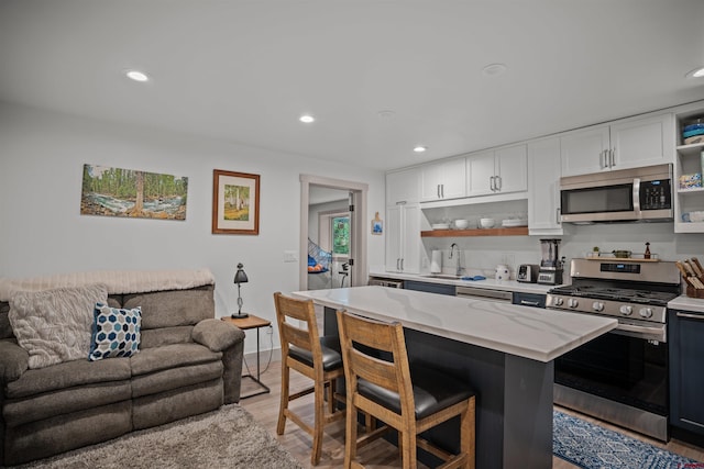 kitchen with light stone counters, white cabinets, stainless steel appliances, and hardwood / wood-style floors