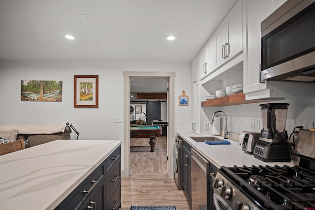 kitchen with white cabinets, stainless steel appliances, light wood-type flooring, pool table, and sink