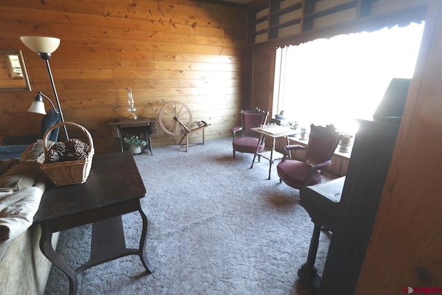 living area with wooden walls, plenty of natural light, and carpet flooring