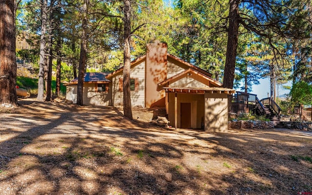 exterior space featuring stairway, a wooden deck, and a chimney
