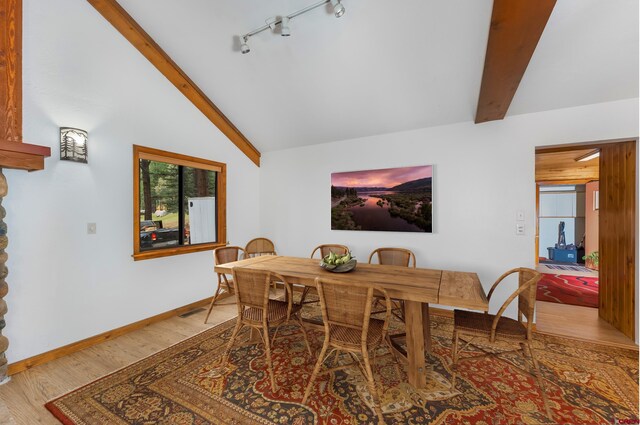 dining space featuring rail lighting, visible vents, wood finished floors, vaulted ceiling with beams, and baseboards