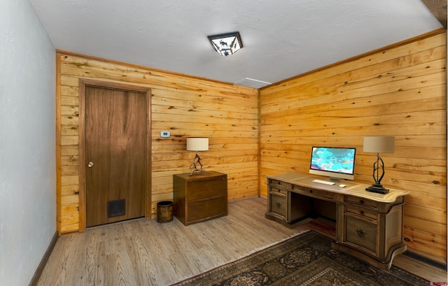 office area featuring wood walls, light wood-style floors, and baseboards