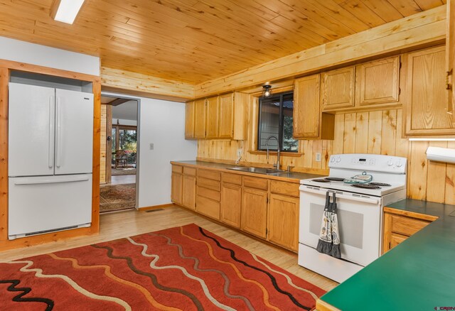 kitchen with a sink, white appliances, wood ceiling, light wood finished floors, and wood walls