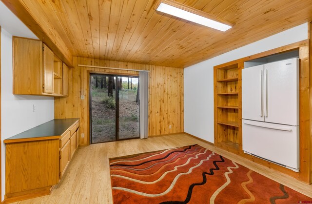 interior space featuring wood ceiling, light wood finished floors, baseboards, and wooden walls