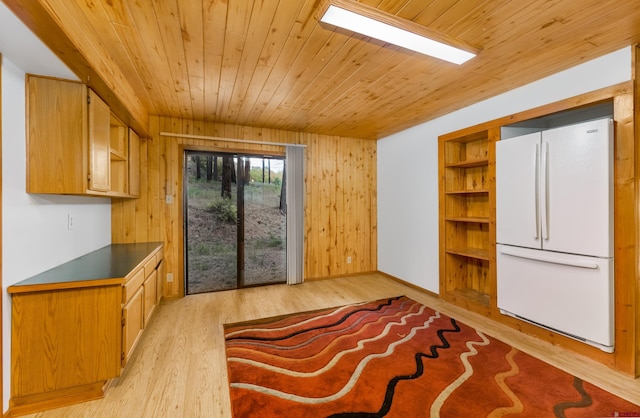 interior space featuring wooden ceiling, light wood-type flooring, white fridge, and wooden walls