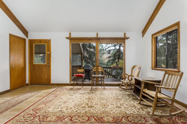 living area featuring baseboards, wood finished floors, and lofted ceiling with beams