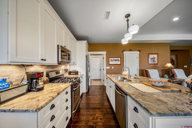 kitchen with dark hardwood / wood-style floors, sink, white cabinetry, appliances with stainless steel finishes, and decorative light fixtures