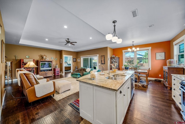 kitchen with light stone counters, dark wood-type flooring, sink, white cabinetry, and decorative light fixtures