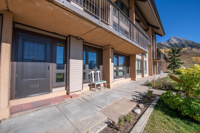 entrance to property featuring a patio, a balcony, and a mountain view