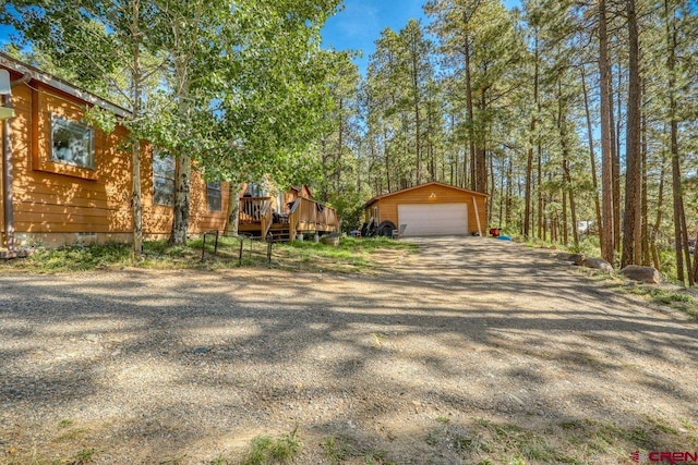 view of front of house with a garage, a deck, and an outbuilding