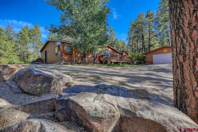 view of front of home featuring a garage, an outdoor structure, and a deck