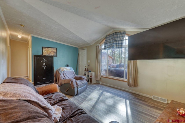 living room with a textured ceiling, crown molding, light hardwood / wood-style floors, and vaulted ceiling