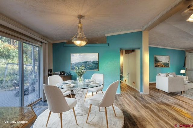 dining area featuring wood-type flooring, a textured ceiling, and crown molding