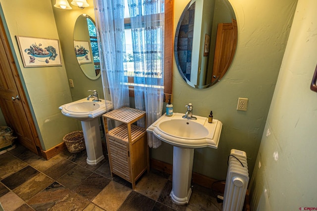 bathroom with radiator and dual sinks