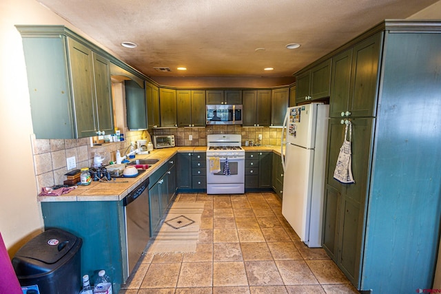 kitchen with backsplash, light tile patterned flooring, sink, and appliances with stainless steel finishes