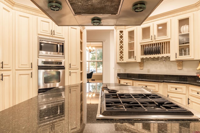 kitchen featuring dark stone countertops, stainless steel appliances, and cream cabinetry