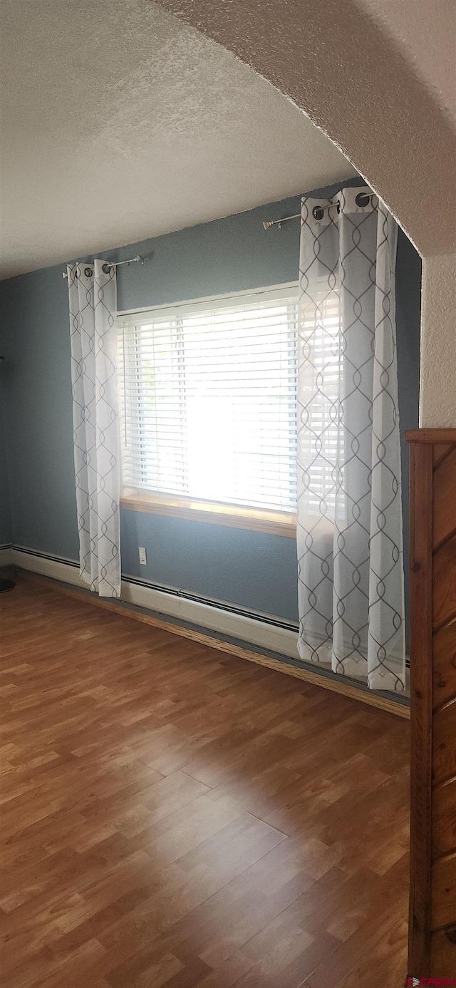 spare room featuring a textured ceiling and wood-type flooring